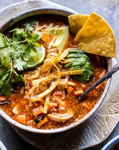 a bowl of chili with tortilla chips and avocado on the side