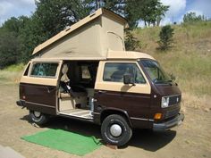 an old van is parked in the dirt with its door open and it's tent on top