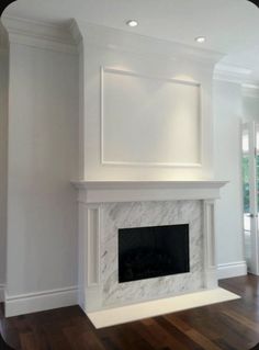 an empty living room with a fireplace and hard wood floors