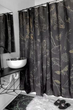 a black and white photo of a bathroom with shower curtain, rug, sink and mirror