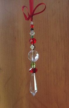 a glass ornament hanging from a red ribbon on a wooden table with other ornaments