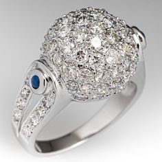 This awesome ring is centered with a domed setting accented with forty-seven (47), bead set, round brilliant cut diamonds. The shoulders of the ring are each accented with one (1), bezel set, round cabochon cut natural sapphire and eight (8), bead set, round brilliant cut diamonds. The ring measures 13.5mm at the top, rises 10.1mm above the finger, tapering to 2.5mm wide and 1.1mm thick at the base of the shank. This ring is currently a size 6.75. Luxury Dome Ring With Center Stone For Formal Events, Luxury Formal Dome Ring With Center Stone, Luxury Sapphire Ring With Round Stone For Formal Occasions, Elegant Dome Ring With Center Stone For Anniversary, Luxury Round Cut Sapphire Ring With Pave Setting, Luxury 14k White Gold Diamond Ring With Round Stone, Brilliant Cut Diamond Dome Ring With Round Band, Dazzling Sapphire Ring With Pave Setting, White Diamond Dome Ring For Formal Occasions