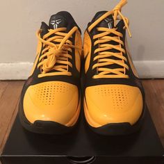 a pair of yellow and black shoes on top of a box with the shoe laces down