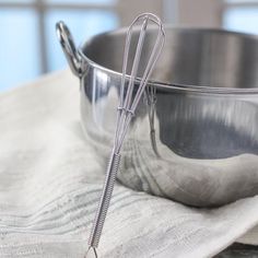 a metal bowl with a whisk in it on top of a white towel