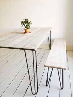 a wooden table with two metal legs and a potted plant sitting on top of it