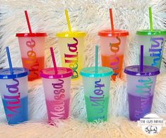 six different colored tumblers with straws sitting on top of a white furnishing