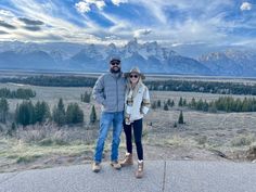 a man and woman standing on top of a mountain