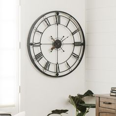 a living room with a large clock on the wall and a plant in front of it