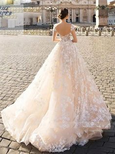 a woman in a wedding dress standing on a cobblestone street with a cathedral in the background