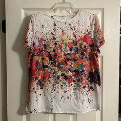 a t - shirt hanging on a door with paint splatters all over it