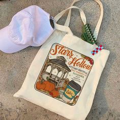 a white tote bag sitting on top of a cement floor next to a hat