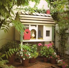 a bird house with flowers and potted plants around it