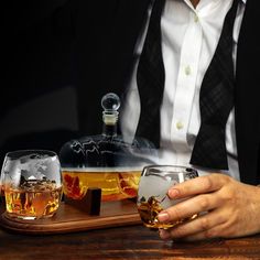 a man sitting at a table with two glasses and a decanter