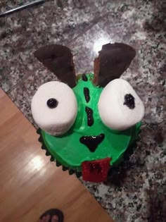 a cupcake with green frosting and two eyes