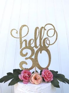 a white cake topped with a gold hello 30th birthday cake topper and pink flowers