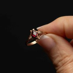 Discover the timeless elegance of our 10k yellow gold triangle garnet ring. This exquisite piece features a bezel-set triangular garnet, complemented by two side bezel-set seed pearls. The pearls are placed in the split shoulder area, adding a delicate touch to the design. Curved and elegant motifs frame the central stone, enhancing the ring's sophisticated appearance. Details: Material: 10k Yellow Gold Main Stone: Triangle Garnet Stone Size: 4.35mm x 6.9mm Accent Stones: 2 Seed Pearls Design: C Triangle Stone Ring, Timeless Garnet Jewelry For Anniversary, Formal Garnet Jewelry With Bezel Setting, Wedding Garnet Birthstone Ring With Bezel Setting, Heirloom Garnet Jewelry With Bezel Setting, Three Stone Garnet Jewelry For Anniversary, Garnet Three-stone Wedding Jewelry, Elegant Trillion Cut Birthstone Rings, Formal Three Stone Garnet Jewelry