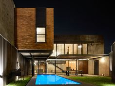 a house with a swimming pool in front of it at night, and lit up by lights