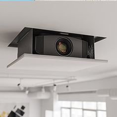 a camera mounted to the side of a ceiling in a room with white walls and windows