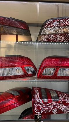 several red cars with white designs on them in a display case at a car dealership