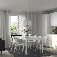 a white dining table and chairs in a room with curtains on the window sill