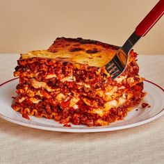 a fork sticking into a stack of lasagna casserole on a plate