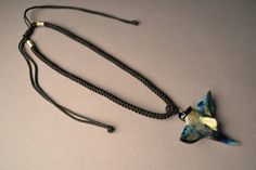 a necklace with a bird shaped pendant hanging from it's side on a cord