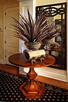 a wooden table topped with a vase filled with lots of dried grass next to a mirror