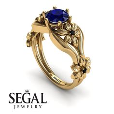 a ring with an oval blue stone surrounded by leaves and flowers on the side, set in 18k rose gold