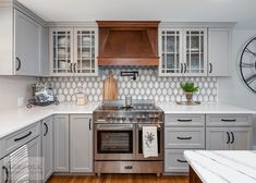 a kitchen with stainless steel appliances and white counter tops is pictured in this image, there are clocks on the wall above the stove