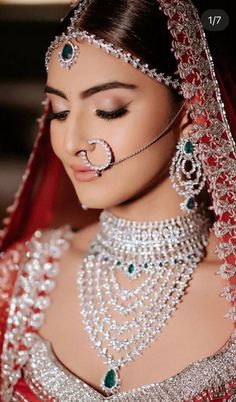 a woman in a red and white bridal outfit with jewels on her head, wearing a