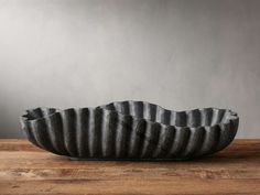 a black and white bowl sitting on top of a wooden table next to a gray wall