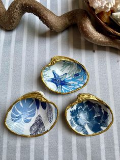 three blue and white dishes sitting on top of a table next to a tree branch