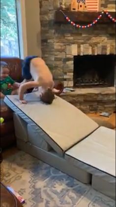 a man standing on top of a mattress in front of a fire place