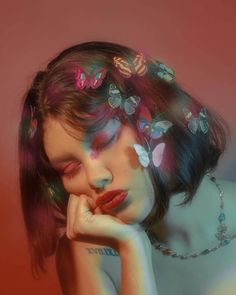 a woman with butterflies on her head and hands near her face, posing for the camera