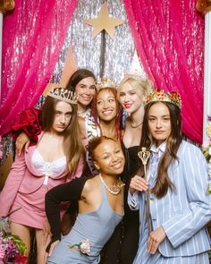 a group of young women posing for a photo in front of a backdrop with pink drapes