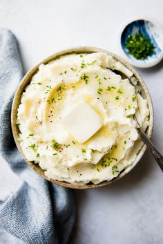 a bowl filled with mashed potatoes topped with butter and seasoning next to a spoon