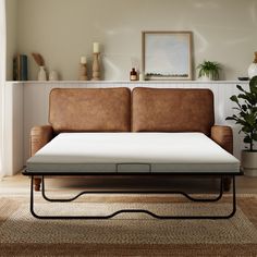 a couch with a mattress sitting on top of it next to a potted plant