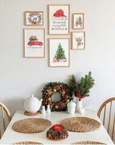 a dining room table with place settings and pictures on the wall above it, decorated for christmas