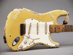 an old yellow electric guitar sitting on top of a table