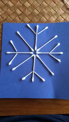 a snowflake made out of sticks on top of a blue piece of paper