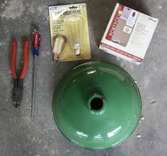 the contents of a green light bulb sitting on top of a cement floor next to tools