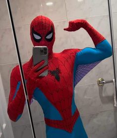 a man dressed as spider - man taking a selfie in front of a mirror