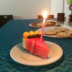 a slice of watermelon cake on a plate with a lit candle in the middle