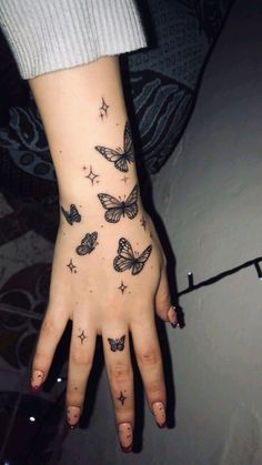 a woman's hand with butterflies on it and stars all over the middle finger