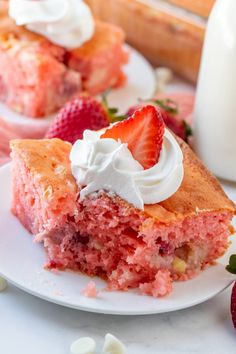 a piece of strawberry cake on a plate with whipped cream and strawberries next to it