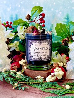 a blue candle surrounded by christmas decorations and greenery on a wooden table with snowflakes in the background