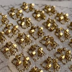 several pieces of gold colored metal with small squares and rectangles on a table cloth