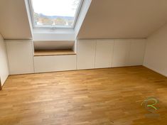 an empty room with wooden floors and skylight in the corner on the top floor