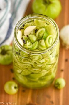 a jar filled with sliced green apples on top of a wooden table