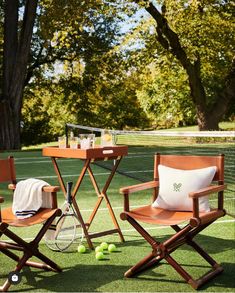 two chairs and a table with tennis balls on the grass